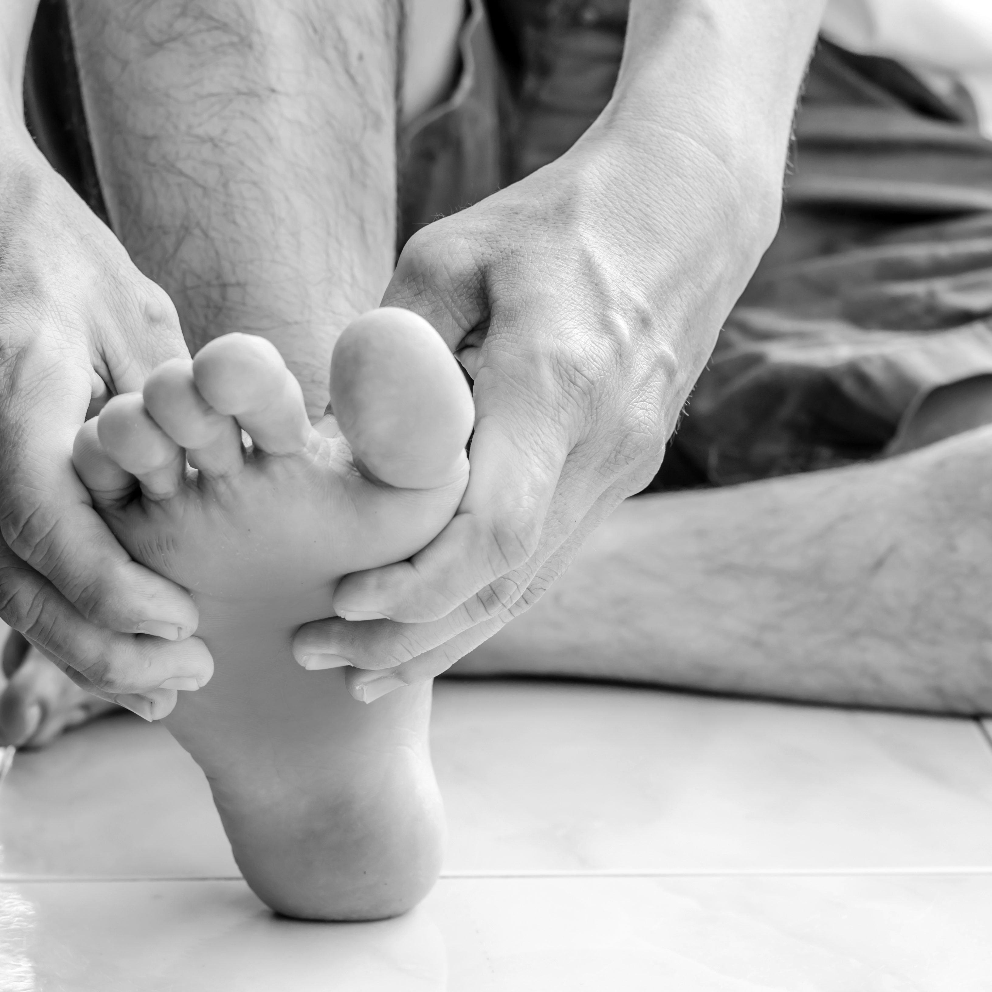 man holding foot on gray background